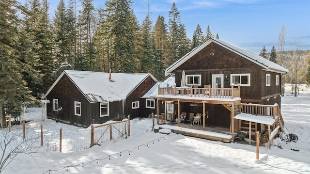 snow covered back of property featuring a deck