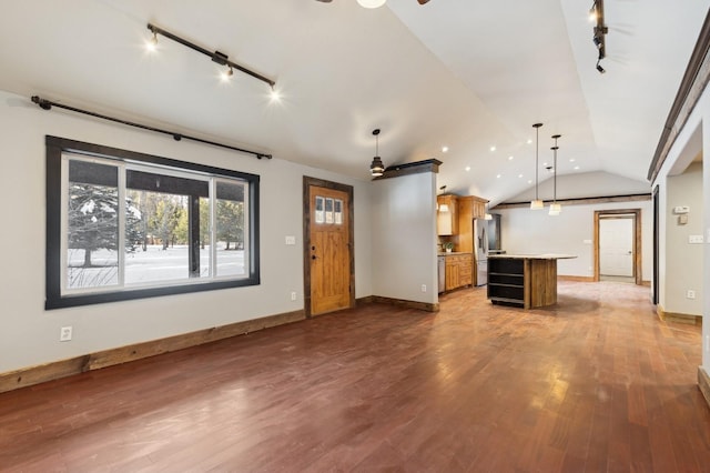 unfurnished living room with dark hardwood / wood-style flooring, vaulted ceiling, and rail lighting