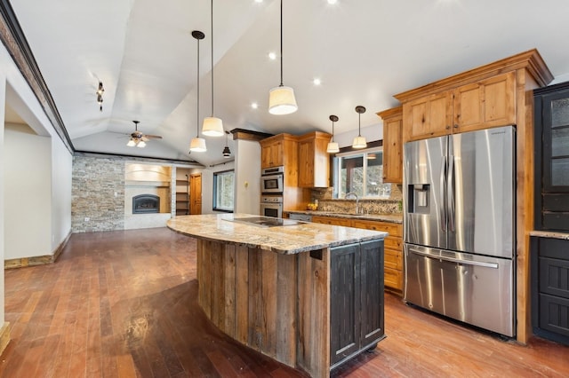 kitchen with a kitchen island, appliances with stainless steel finishes, pendant lighting, lofted ceiling, and decorative backsplash