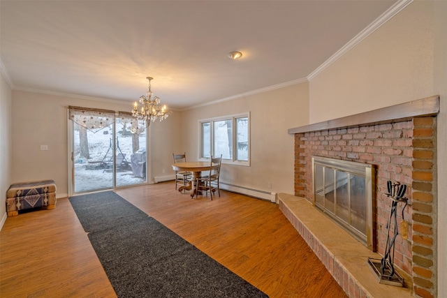 dining area with ornamental molding, wood-type flooring, a fireplace, and a chandelier