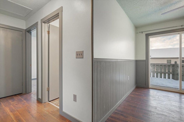 corridor with a textured ceiling and dark hardwood / wood-style flooring