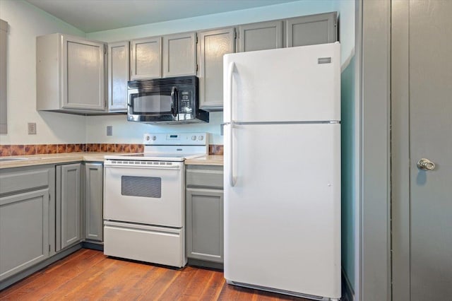 kitchen featuring hardwood / wood-style flooring, white appliances, and gray cabinets