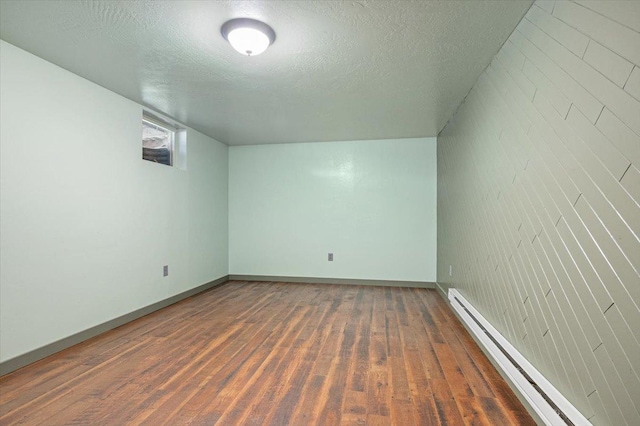 bonus room with a baseboard heating unit, dark wood-type flooring, and a textured ceiling