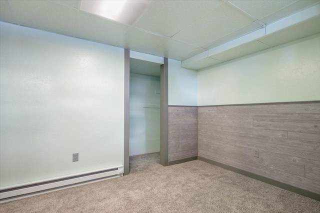 carpeted spare room featuring a drop ceiling and baseboard heating