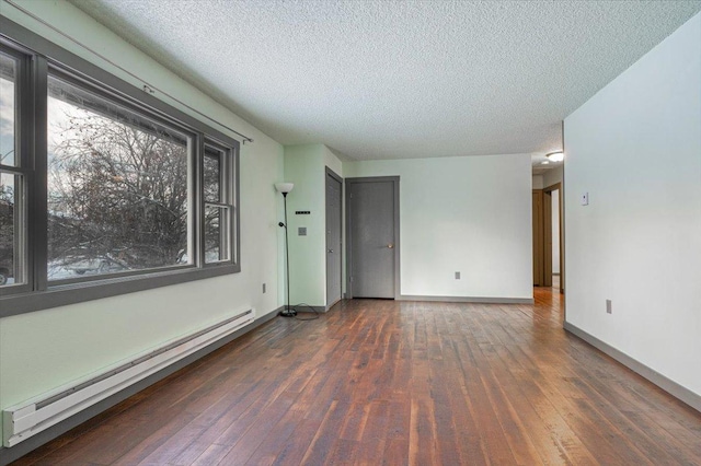 spare room with dark wood-type flooring, a textured ceiling, and baseboard heating