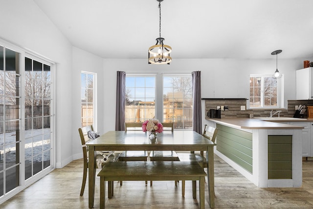 dining area featuring light wood-style flooring, a notable chandelier, and baseboards