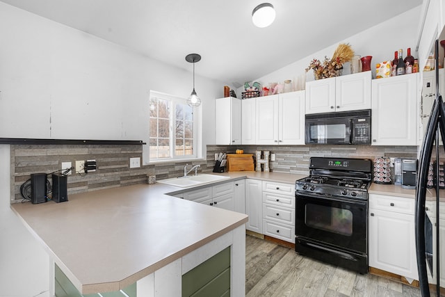 kitchen with a sink, light countertops, decorative light fixtures, black appliances, and a peninsula