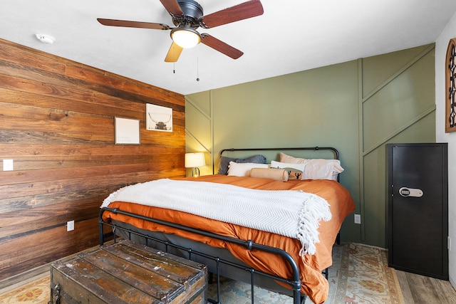 bedroom with a ceiling fan and wood walls