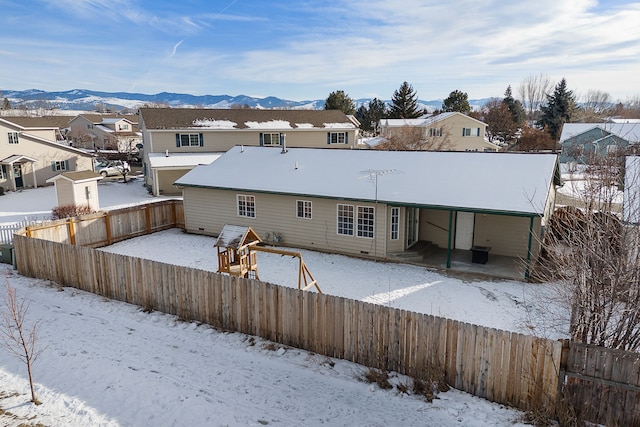 snow covered rear of property with central air condition unit, a mountain view, a residential view, and fence private yard