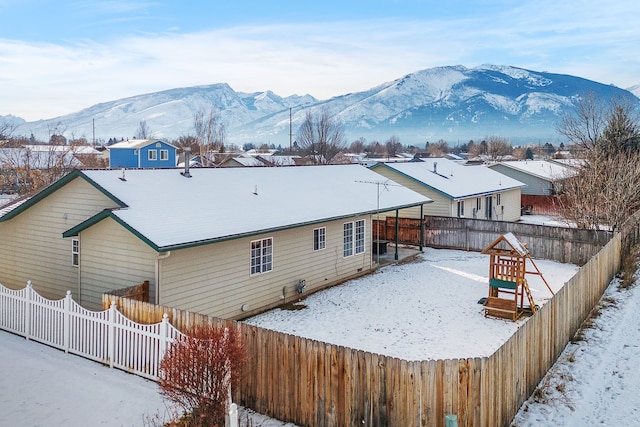 exterior space with a mountain view, a fenced backyard, and a playground