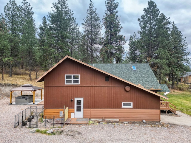 view of side of property featuring a gazebo and a hot tub