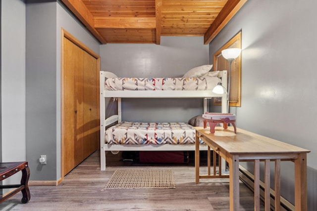 bedroom with hardwood / wood-style floors, wood ceiling, baseboard heating, beam ceiling, and a closet