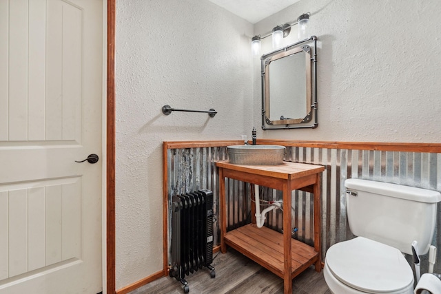 bathroom with radiator, wood-type flooring, and toilet