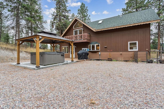 rear view of property with a gazebo, a balcony, a hot tub, and a patio area