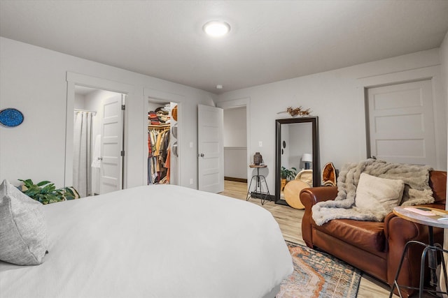 bedroom with a walk in closet, light hardwood / wood-style floors, and a closet