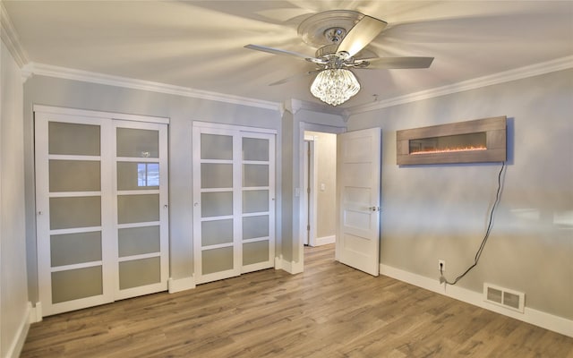 empty room with crown molding, wood-type flooring, and ceiling fan