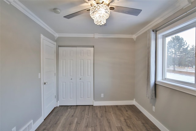 unfurnished bedroom with crown molding, ceiling fan, a closet, and hardwood / wood-style flooring