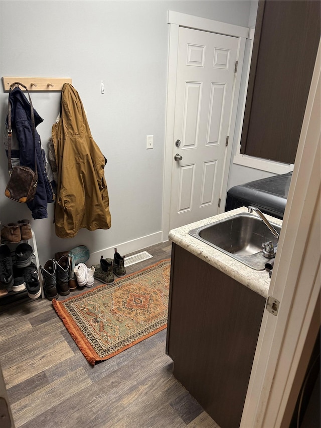 clothes washing area with sink and dark wood-type flooring