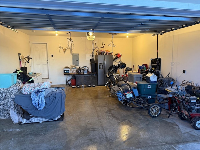 garage with a garage door opener, stainless steel refrigerator with ice dispenser, and electric panel