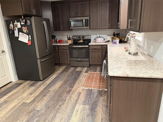 kitchen featuring stainless steel appliances, dark brown cabinets, sink, and dark hardwood / wood-style floors