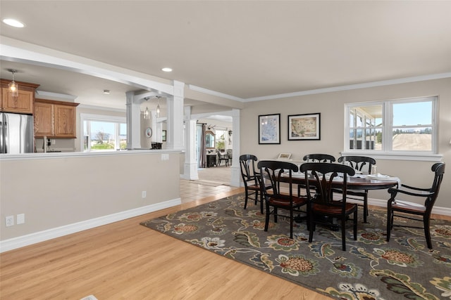 dining space with crown molding, plenty of natural light, and light hardwood / wood-style floors