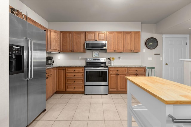 kitchen featuring light stone counters, light tile patterned flooring, and appliances with stainless steel finishes