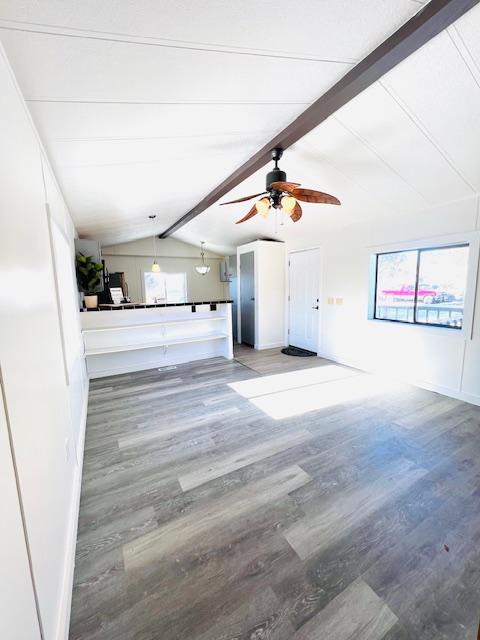 unfurnished living room featuring wood-type flooring, lofted ceiling with beams, and ceiling fan