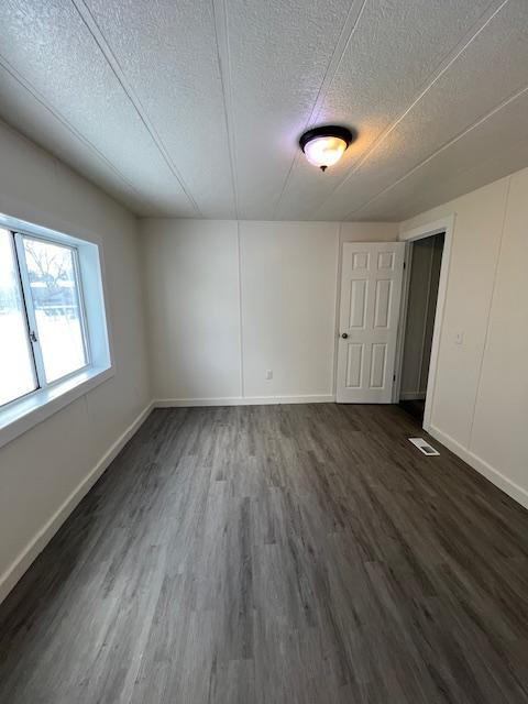 spare room featuring dark hardwood / wood-style flooring and a textured ceiling