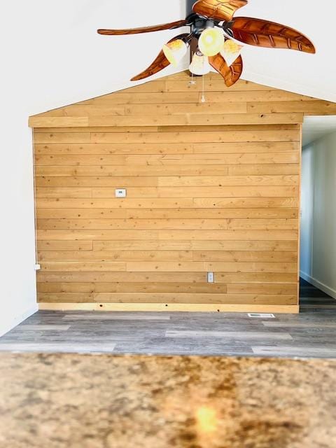 details with hardwood / wood-style flooring, ceiling fan, and wooden walls