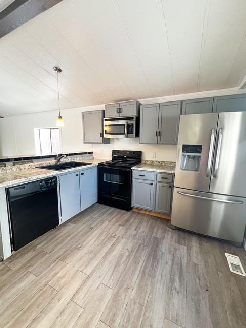 kitchen with light hardwood / wood-style floors, sink, hanging light fixtures, and black appliances