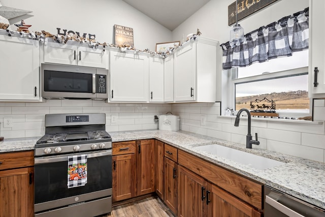 kitchen with appliances with stainless steel finishes, sink, decorative backsplash, and white cabinets