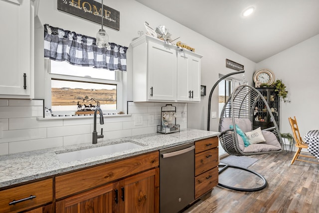 kitchen with white cabinets, decorative backsplash, light stone countertops, and dishwasher