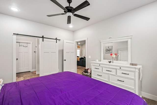 unfurnished bedroom with a barn door and ceiling fan