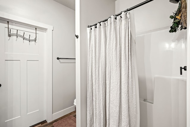 bathroom featuring hardwood / wood-style flooring, toilet, and walk in shower