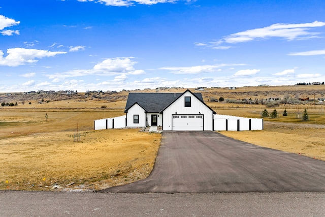 view of front of property featuring a garage and a rural view