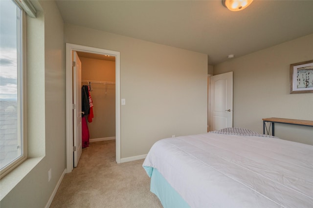 bedroom featuring a spacious closet, light carpet, and a closet