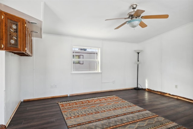 empty room with ornamental molding, dark hardwood / wood-style floors, and ceiling fan