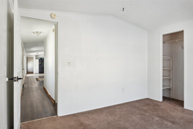 unfurnished bedroom featuring lofted ceiling, black refrigerator with ice dispenser, and dark colored carpet