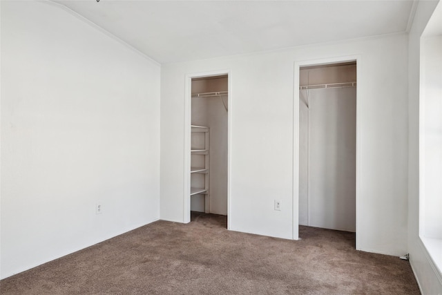 unfurnished bedroom with multiple closets and carpet floors