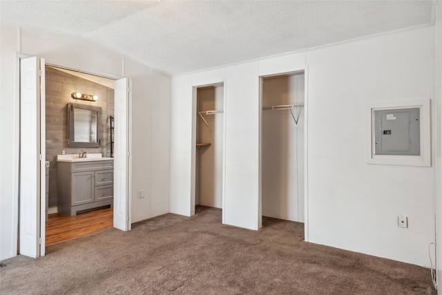 unfurnished bedroom with vaulted ceiling, ensuite bath, carpet floors, electric panel, and a textured ceiling