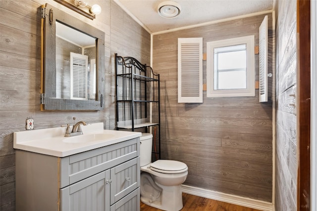 bathroom featuring vanity, toilet, crown molding, and wood walls