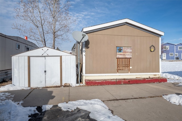 view of snow covered exterior with a storage shed