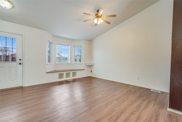 unfurnished living room with ceiling fan, vaulted ceiling, and light wood-type flooring