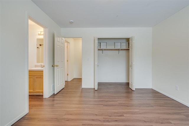 unfurnished bedroom featuring ensuite bathroom, sink, light hardwood / wood-style flooring, and a closet