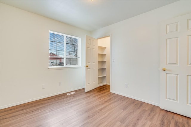 unfurnished bedroom featuring a walk in closet and light hardwood / wood-style floors