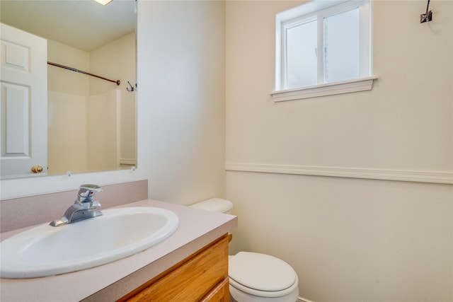 bathroom with walk in shower, vanity, and toilet