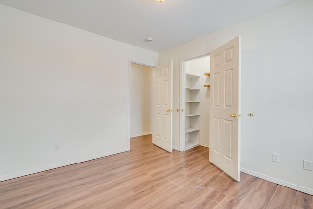 unfurnished bedroom with a walk in closet and light wood-type flooring