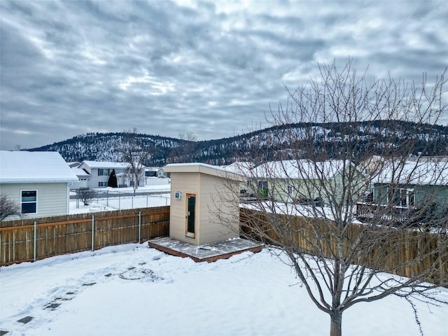 yard covered in snow with a mountain view and a storage unit