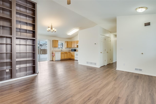 unfurnished living room featuring hardwood / wood-style flooring, sink, a chandelier, and vaulted ceiling