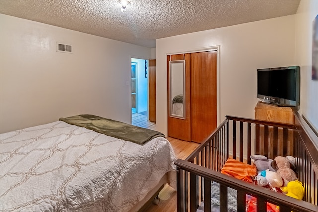 bedroom with hardwood / wood-style floors, a closet, and a textured ceiling